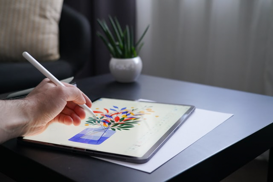 Close up of someone drawing flowers in a vase on a tablet