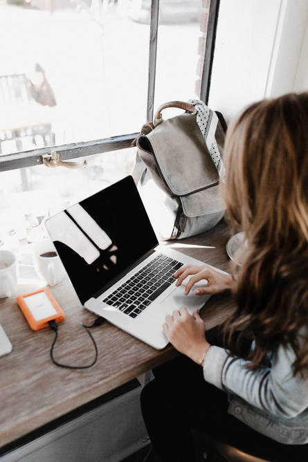 Close up of a woman working on a laptop on a wooden desk