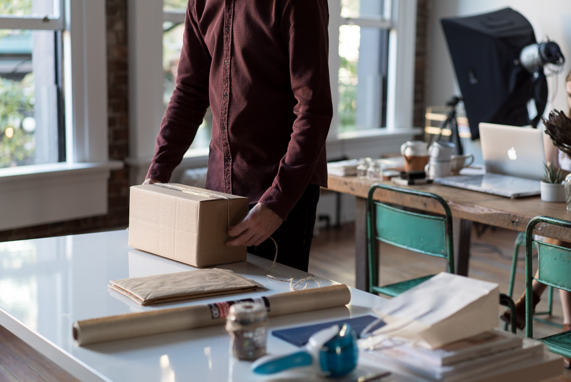 A person working with a cardboard box on a table in a studio environment.