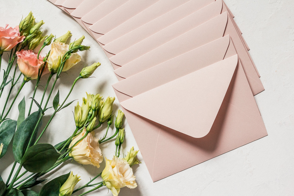 Pink enevelopes and flowers on a white background.