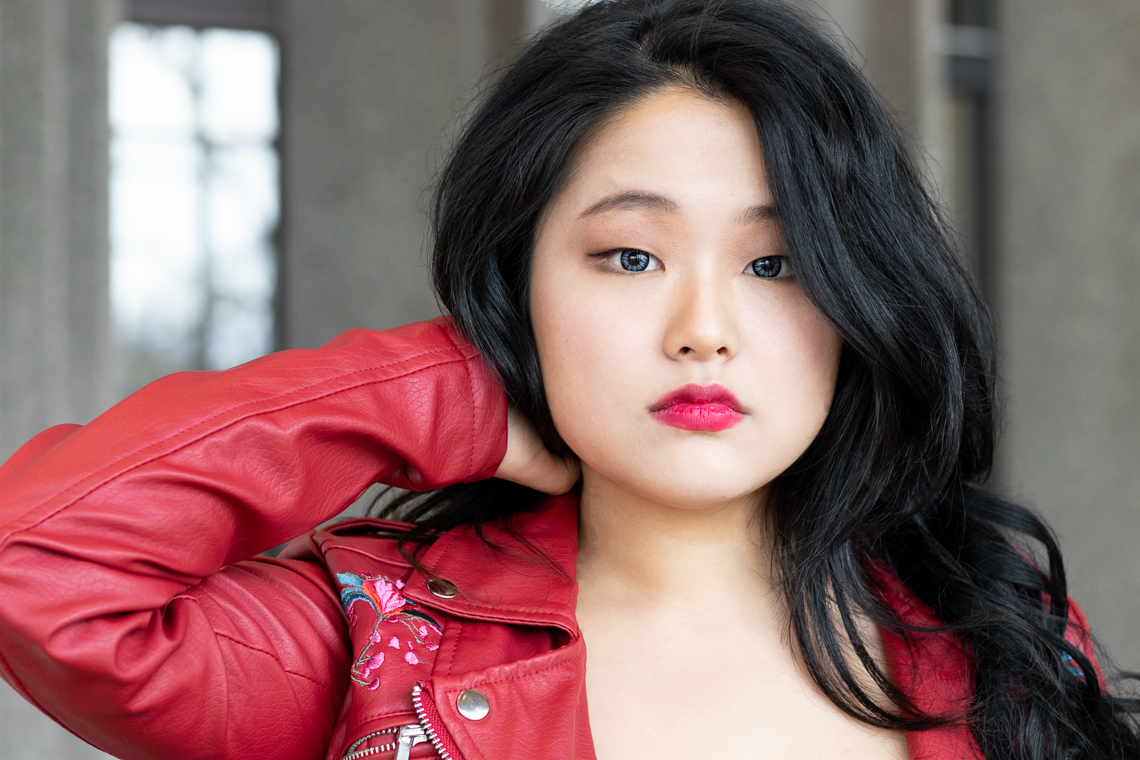 Asian woman modeling. She is wearing a red jacket and red lipstick.