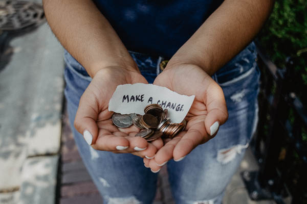 Close-up of a person holding some change with a note that says Make a Change