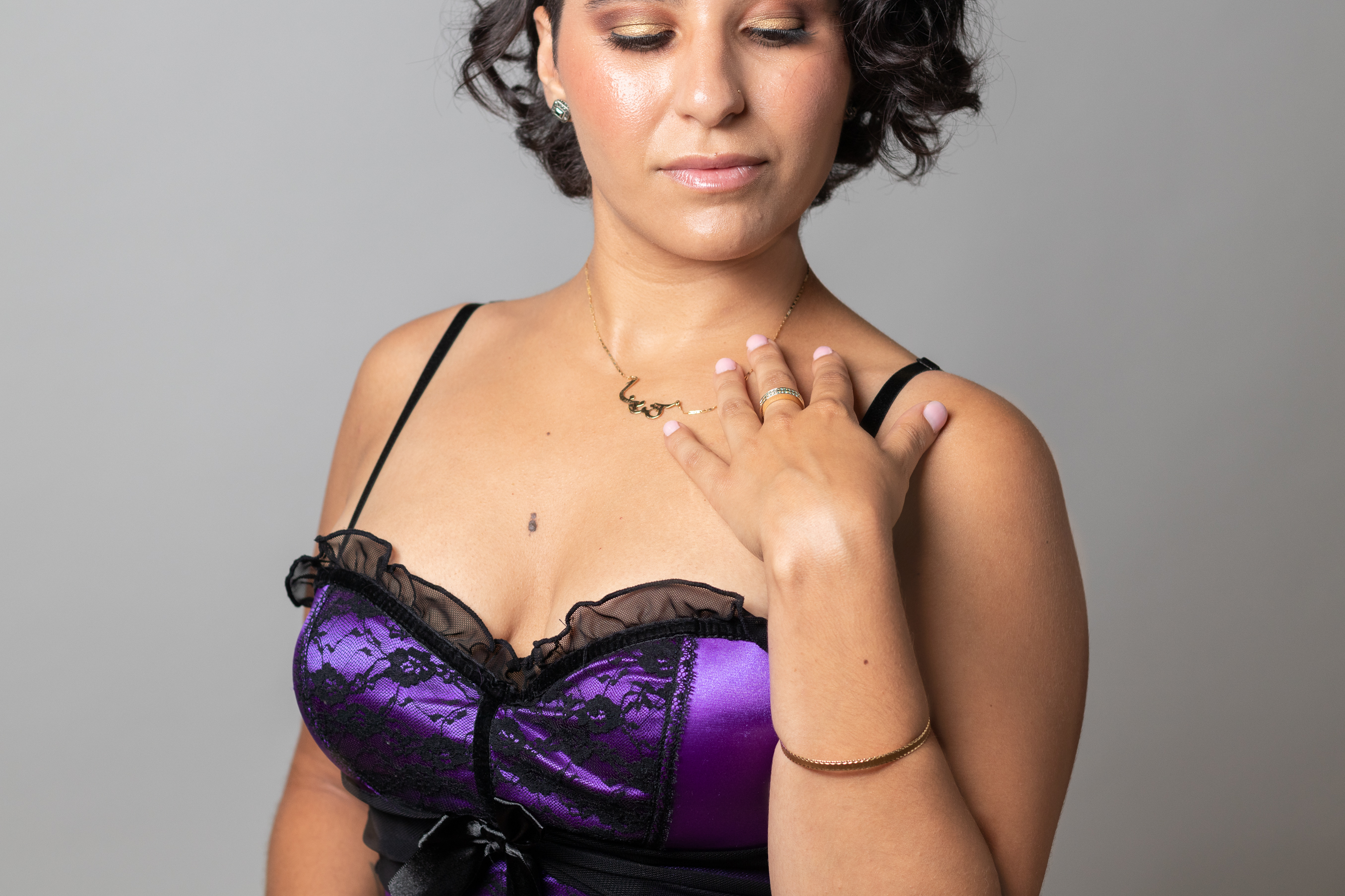 Black-haired woman in a purple bustier looking down.