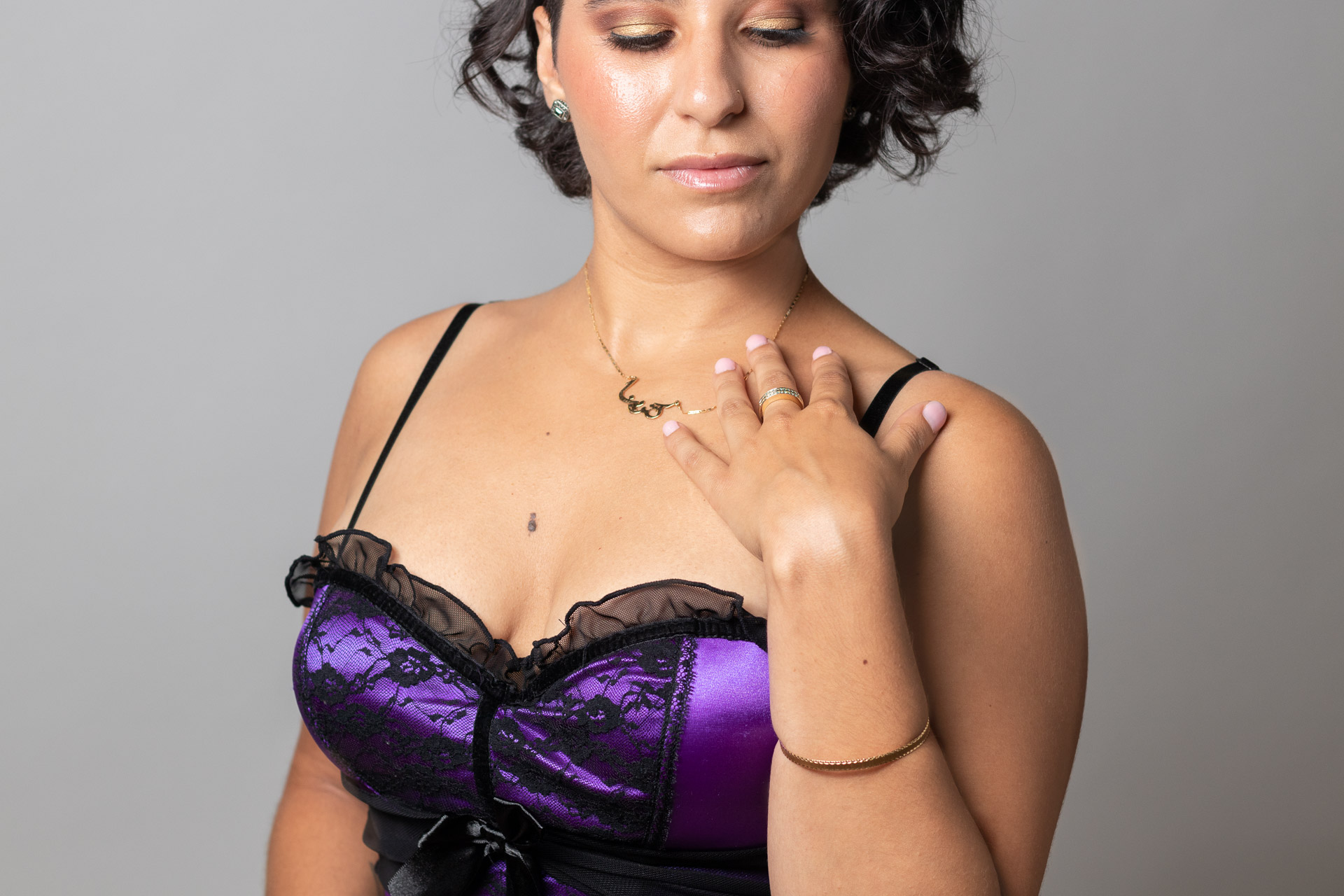 Black-haired woman in a purple bustier looking down
