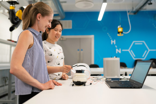 Two young women working on a robotics project in a lab.