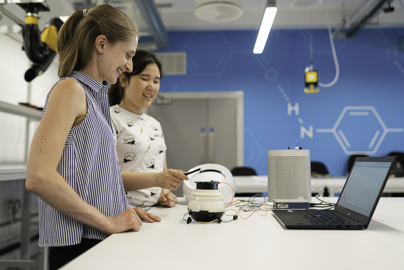 Two young women working on a robotics project in a lab.