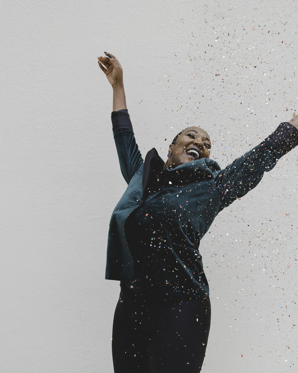 Black woman jumping in the air with confetti