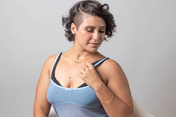 Headshot of a woman with short black hair in a blue camisole looking at her shoulder.