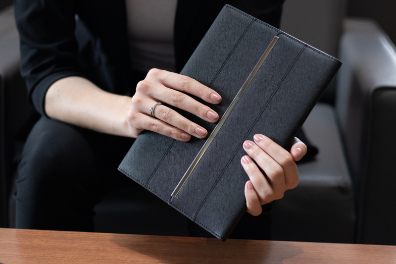 Woman holding a leather notebook with a gold trim.