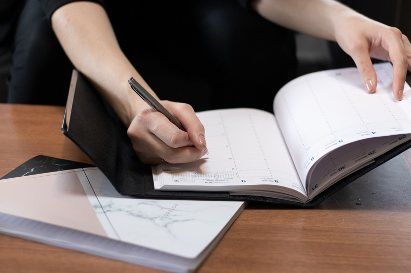 Woman writing in a planner.