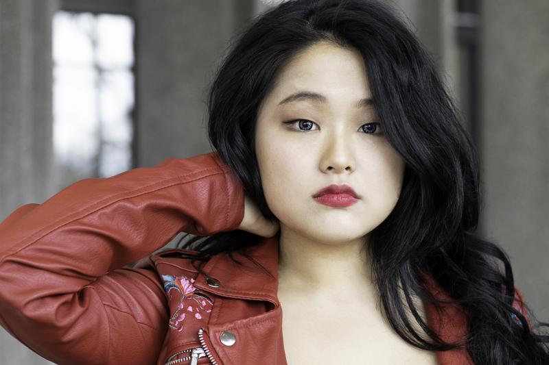 Asian woman modeling. She is wearing a red jacket and red lipstick.