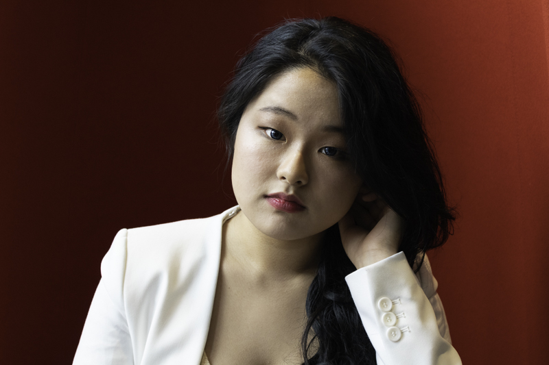 Head shot of an Asian woman on a red background.